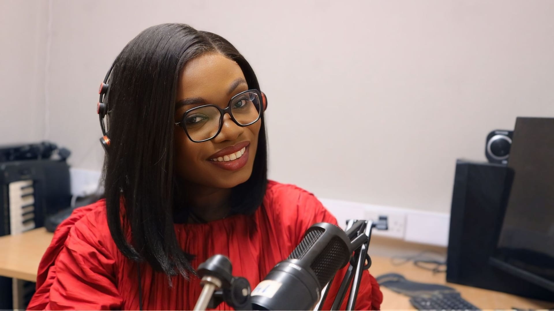DK Jonah smiling at a studio microphone, wearing headphones